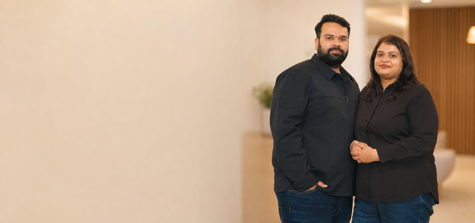 Dr. Swati Verma and Vaibhav Sharma, co-founders of Glamveda, standing side by side in matching black outfits inside a modern warm-lit office