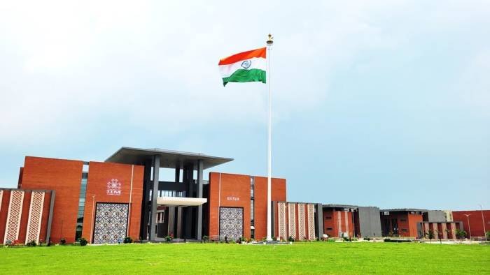IIM Sambalpur permanent campus with the Indian flag flying at the entrance, red-brick administrative block behind