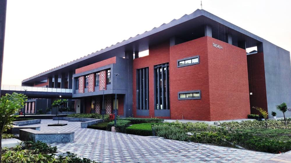 Takshila-I building on the IIM Sambalpur campus, red brick and grey concrete with regional Sambalpuri motifs on the façade